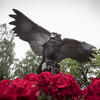 The Owl statue in O'Connor Plaza on Main Campus above red flowers