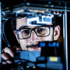 Philip Dames working on his robot in the lab. He's wearing glasses and concentrating.