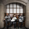 three Fox School of Business faculty members sitting on a bench reading newspapers.